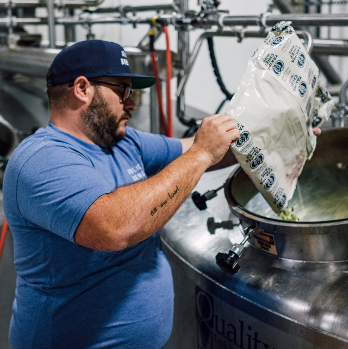 brewer pouring hops into tank